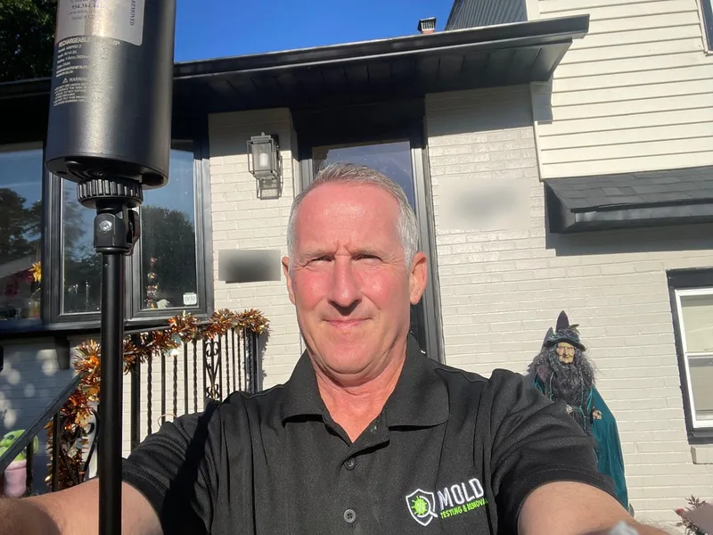 Mold Testing & Removal inspector in a branded uniform on site with an air sampling pump before a mold test in Philadelphia
