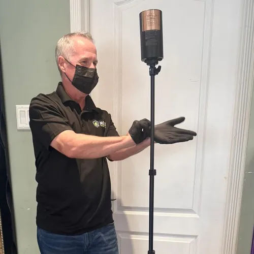 Mold inspector in a mask and gloves setting up an air sampling pump for an indoor air quality test in Philadelphia